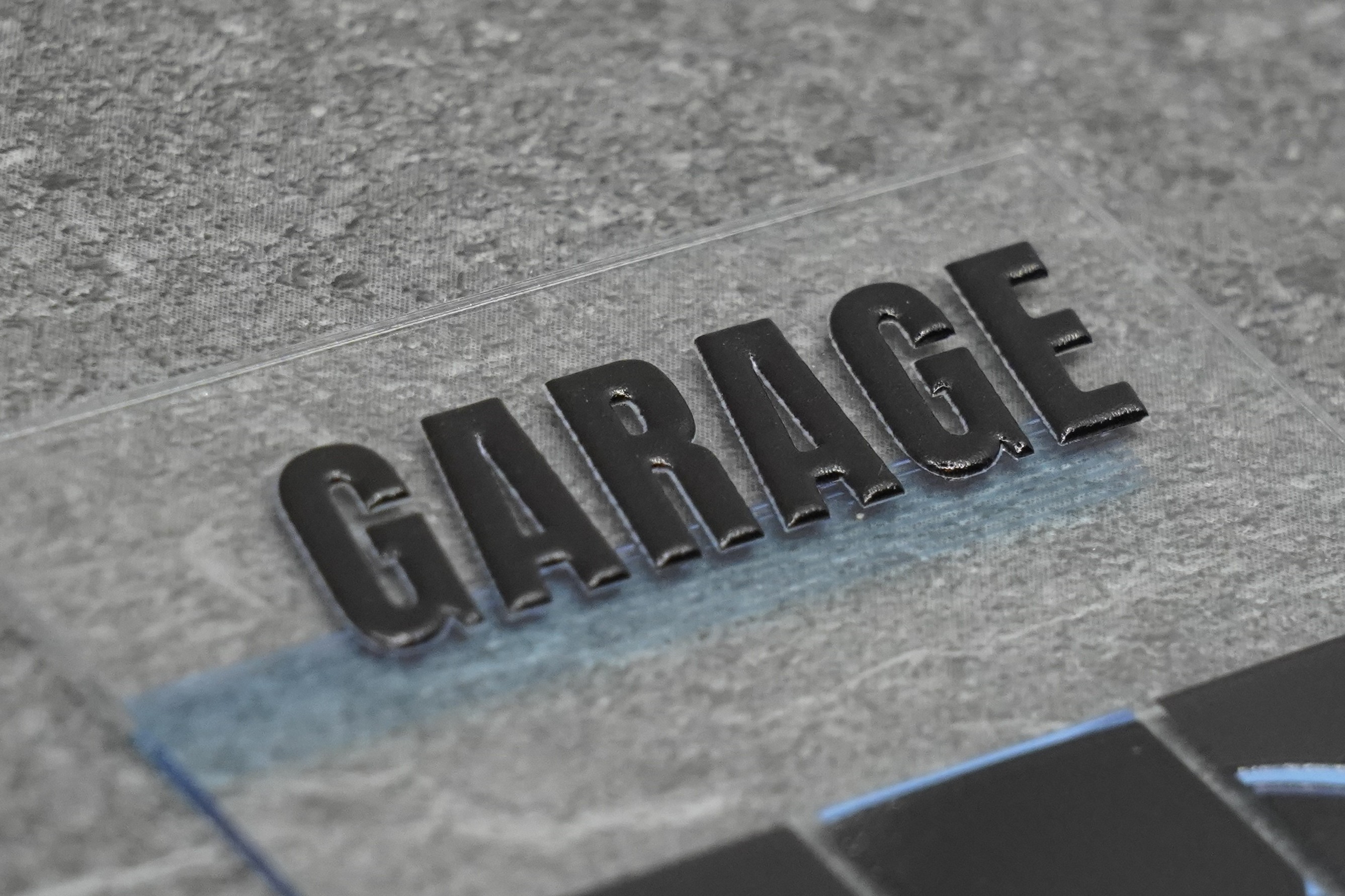 Makro: erhaben gedruckte Buchstaben «GARAGE» auf transparentem Acryl