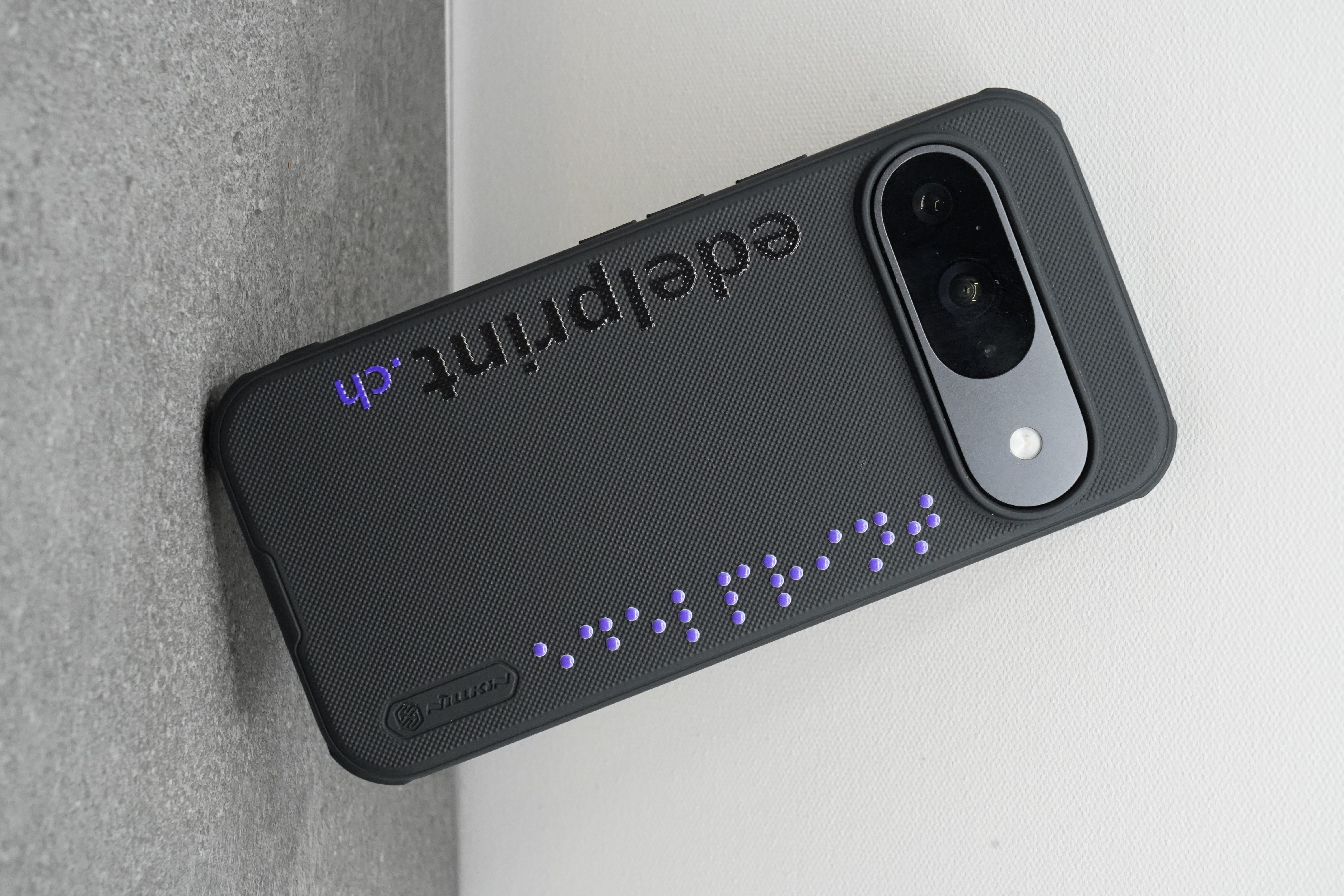 Handyhülle in Schwarz mit erhabenen lila Braille-Punkten und edelprint.ch-Schriftzug in Weissunterdruck